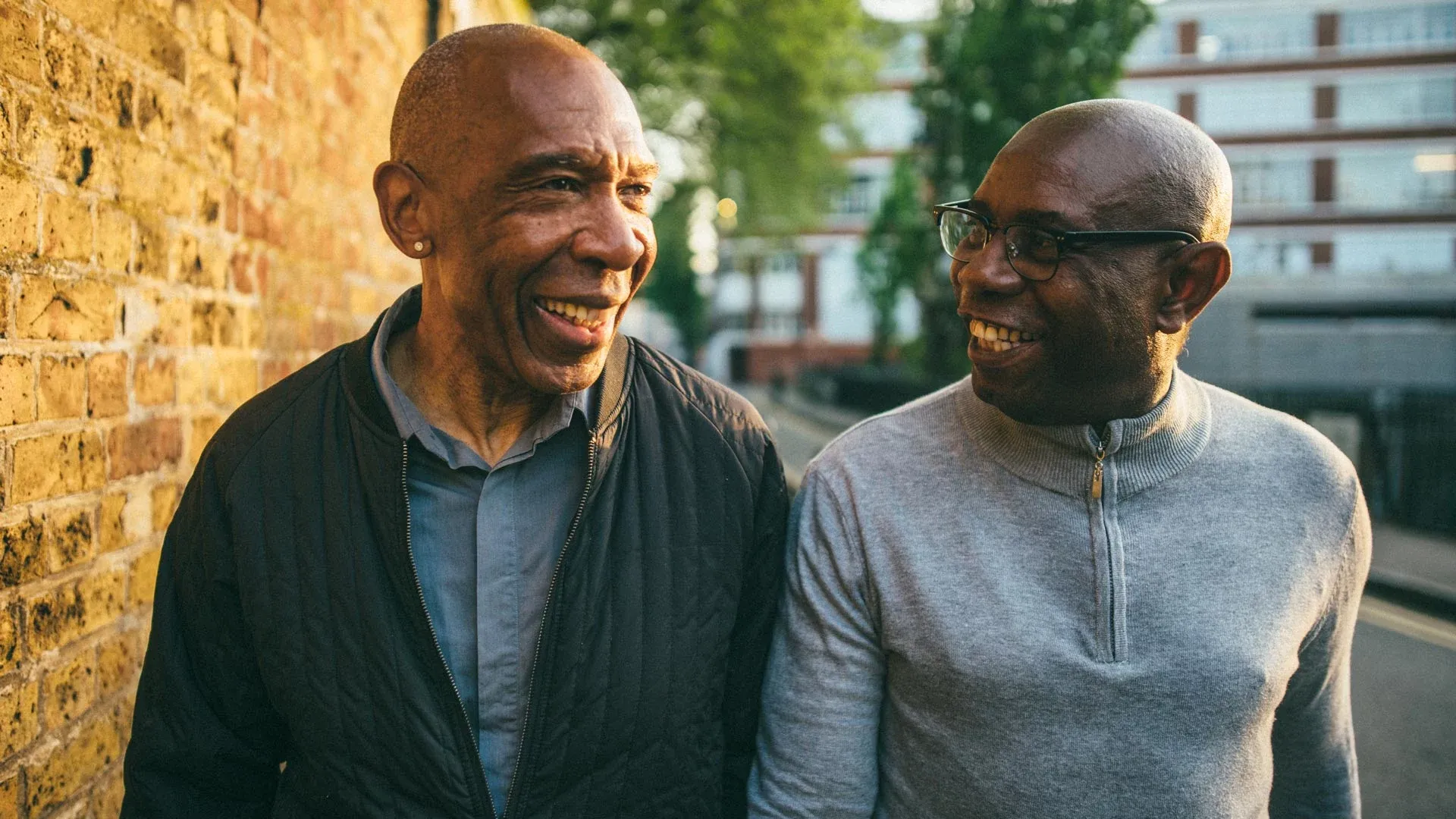 Photo of two middle-aged men, having a lively discussion as they walk vigorously down a street.